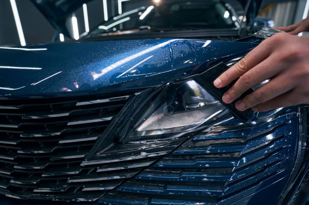 Close up picture of Helmet PPF being installed with a Helmet squeegee on a vehicle headlight
