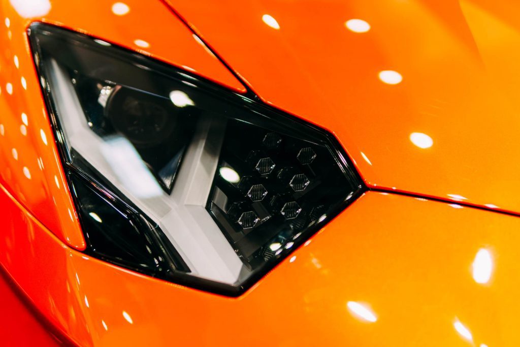 Close up picture of the headlight of a shinny orange sport car